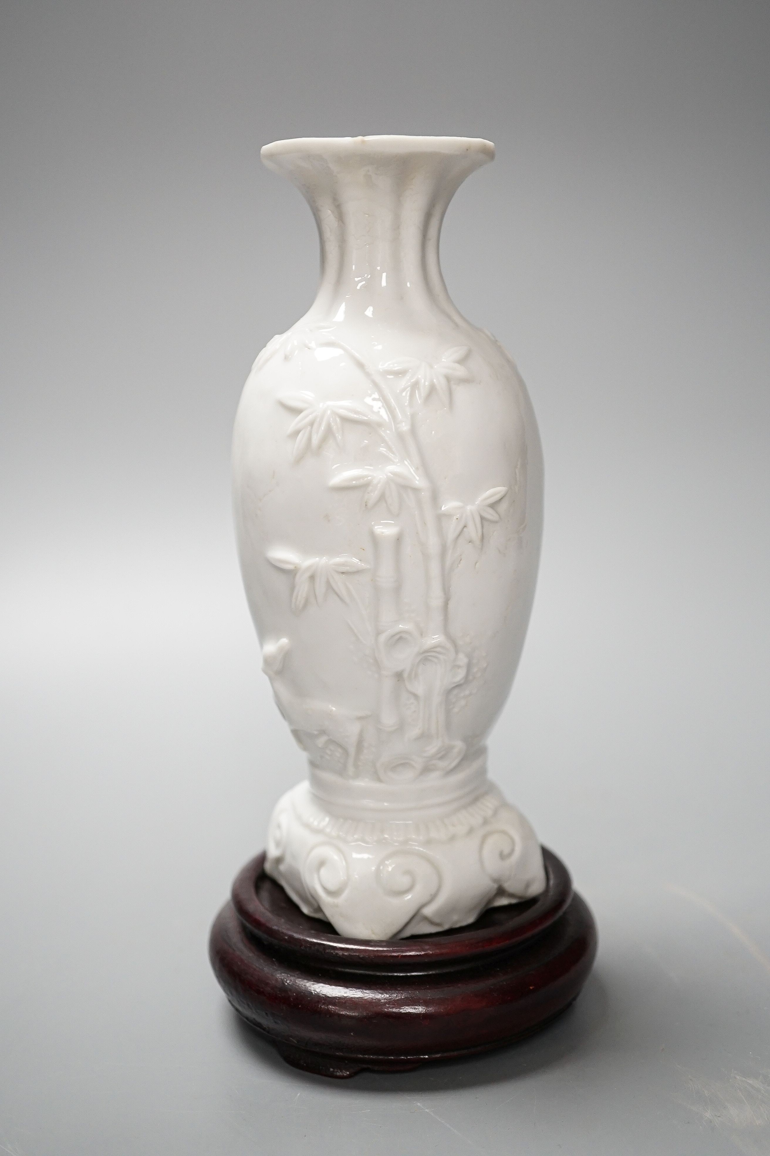 A Chinese 'deer and bamboo' moulded porcelain vase, 19th century, wood stand, height overall 20cm